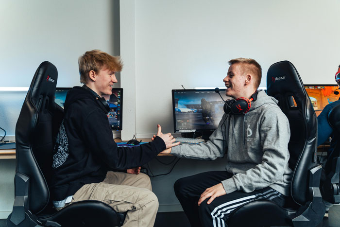 Drenge giver hinanden hånden i gamerrummet på efterskolen skamling hvor de dyrker esport som linjefag